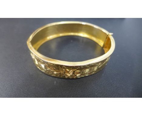 A gold bangle with engraved decoration tested to approx 20ct - 7cm x 6cm - approx weight 29 grams