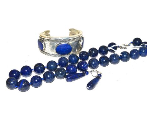 A lapis lazuli bead necklace, a pair of lapis lazuli drop earrings and a lapis lazuli cuff bangle 