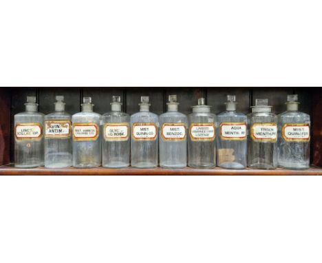 Ten large early 20th century 'label under glass' apothecary bottles and stoppers, each of cylindrical form with faceted recta
