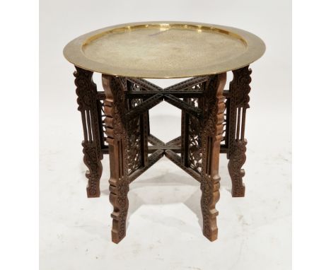 Early 20th century Indian folding table, the circular brass top with chased floral decoration, on a hardwood folding six-legg