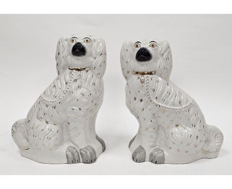 Two late 19th century Staffordshire pottery models of spaniels of large size, each modelled seated, wearing gilt padlock and 