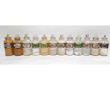 Twelve early 20th century 'label under glass' apothecary bottles and stoppers, each of cylindrical form with assorted faceted