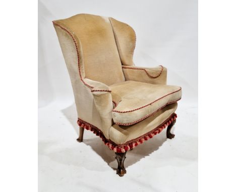 Wingback armchair in the George III manner, with cream upholstery with a pink and red pipe edge, on short front carved cabrio