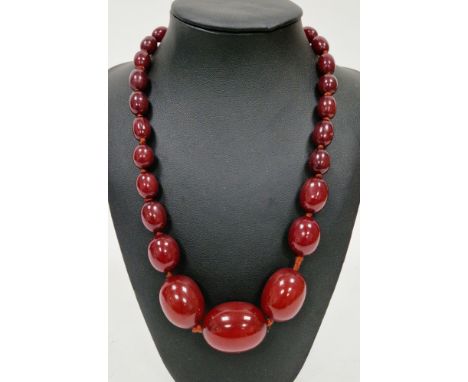 Cherry bakelite amber bead necklace, comprising twenty seven strung graduated oval beads, largest bead 3.4cm long, total leng