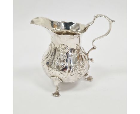 George III silver cream jug, London 1973, makers mark ET(?), of baluster form with wavy rim, scroll loop handle, embossed flo