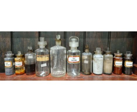 A group of early 20th century glass apothecary bottles and stoppers, each of cylindrical form with assorted faceted rectangul
