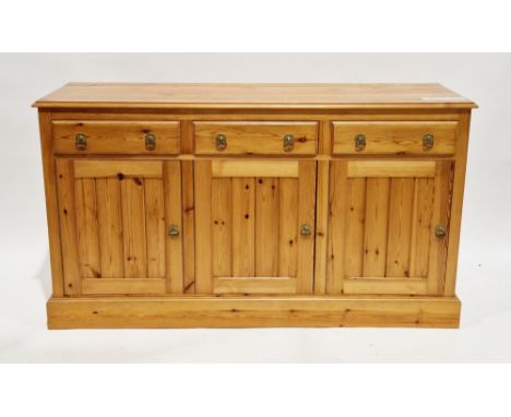 Modern pine dresser base&nbsp;with three frieze drawers and three cupboard doors, having brass drop ring handles, on plinth b