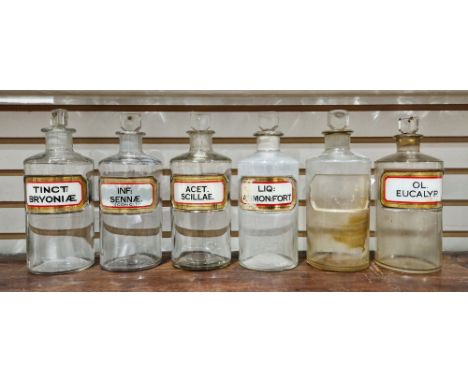 Six early 20th century 'label under glass' apothecary bottles and stoppers, each of cylindrical form with assorted faceted re