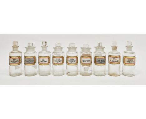 Nine early 20th century 'label under glass' apothecary bottles and stoppers, each of cylindrical form with faceted rectangula