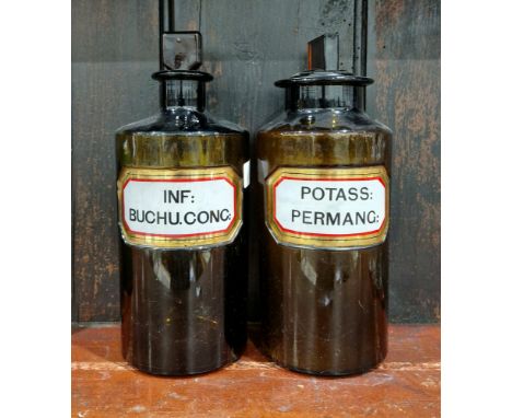 Two large early 20th century brown-tinted 'label under glass' apothecary bottles and stoppers, each of cylindrical form with 