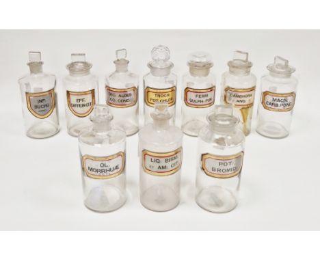 Ten early 20th century 'label under glass' apothecary bottles and stoppers, each of cylindrical form with faceted rectangular