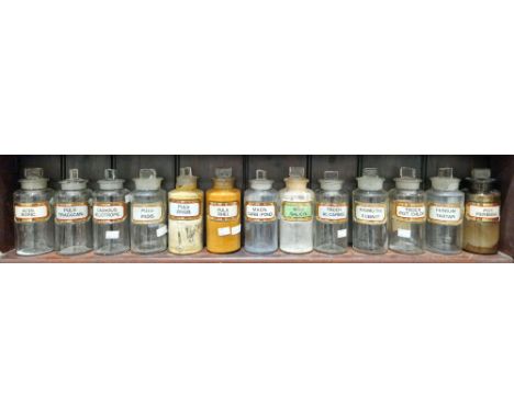Thirteen early 20th century 'label under glass' apothecary bottles and stoppers, each of cylindrical form with assorted facet