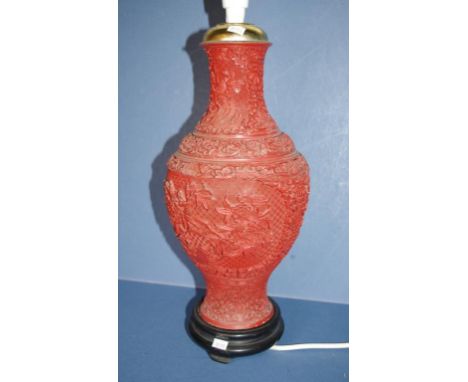 Chinese cinnabar type electric table lamp embossed floral decoration. On wood stand. H44cms approx (total).