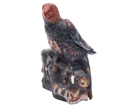 A hardstone model of a bird of prey, seated on a naturalistic carved base, 16cm high.   