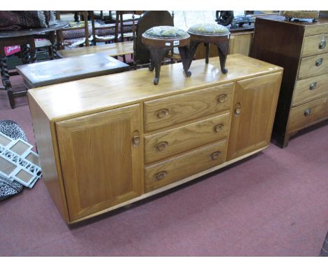 An Ercol Sideboard, light wood with cupboards flanking three drawers, on castors, (one handle damaged) 155.5cm wide.