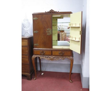 A Mid XX Century Mahogany Drinks Cabinet, with cream and mirrored interior, brass tyre to twin doors, over twin drawers and p