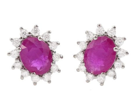 Pair of 18ct white gold oval cut ruby and round brilliant cut diamond cluster stud earrings, stamped 750, total ruby weight a