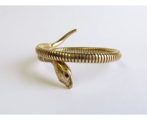 A 9ct gold snake bangle with ruby set eyes and engraved detail to head