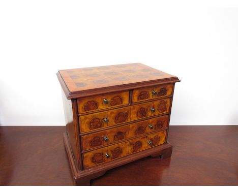 An Oyster veneered miniature chest of two over three drawers raised on bracket feet, 25.5cm x 28cm x 19.5cm