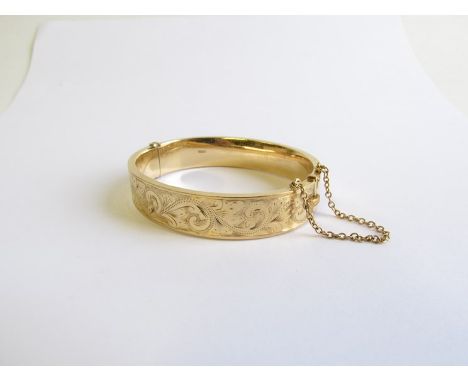 A 9ct gold engraved stiff hinge bangle with safety chain 