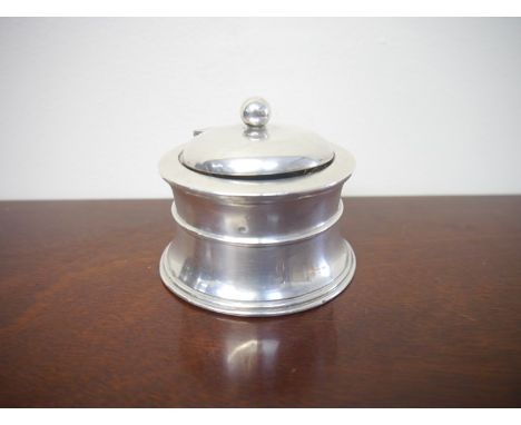 A silver inkwell with ceramic liner, wooden base, marks rubbed from body, slight dents 