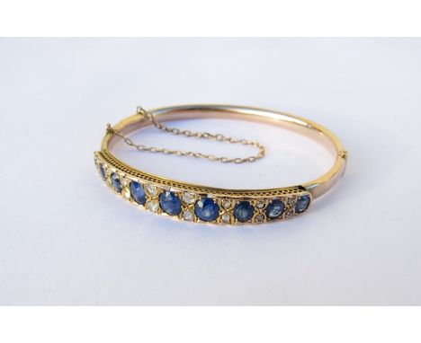 A sapphire and diamond hinge bangle the nine graduated oval sapphires interspersed with twin diamond, unmarked 