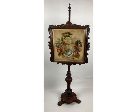 A Victorian mahogany Polescreen, with tapestry panel depicting a large mill house in a landscape with flowers to the fore, on