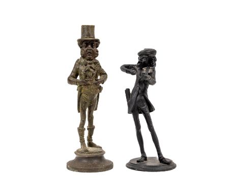 A Spelter model Candlestick, of Dickens Character, together with another similar metal Candlestick, each indistinctly&nbsp;si