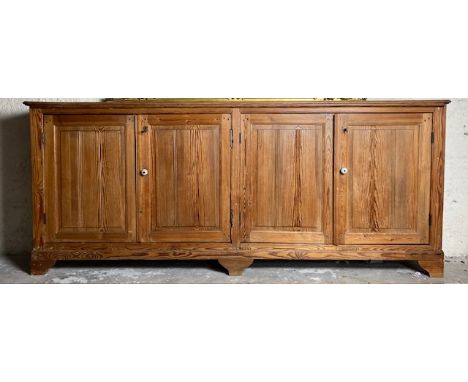 A large late 19th Century four door pitch pine Cupboard, with oblong moulded top raised on bracket feet, 100cms x 240cms (39 