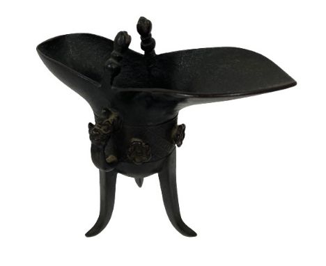 A very good 18th Century bronze Ritual Wine Vessel, Jue, typically standing on a tripod, the deep bowl flanked to one side wi