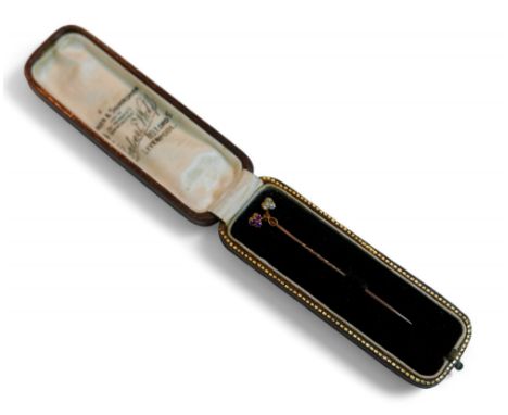 A diamond and ruby yellow metal stick pin, 6.5cm long, 1.6g, with original fitted case.
