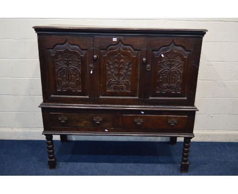 AN 18TH CENTURY AND LATER CARVED OAK TWO DOOR DEUDDARN, carved triple panel front, above two drawers with brassed drop handle