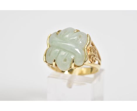 A 14CT GOLD JADE RING, a carved jade panel set within a four claw setting, with Oriental design open work shoulders, to the p