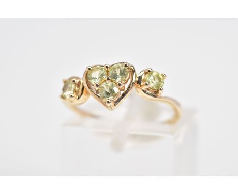 A 9CT GOLD RING, designed with a central heart panel set with three circular cut stones assessed as peridot, with scrolling s