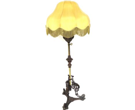 A Victorian brass and cast iron gasolier standard lamp, later converted to electricity, the reservoir embossed with masks of 