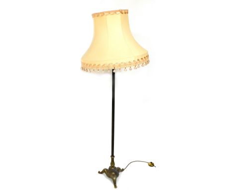 An early 20thC brass standard lamp, with a peach coloured shade, 157cm high.
