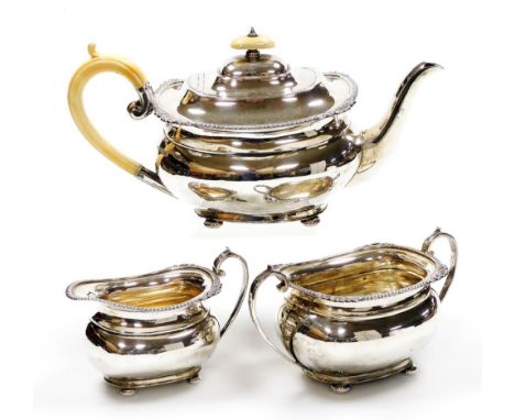 An Edward VII silver three piece tea set, comprising teapot, milk jug and two handled sugar bowl, the teapot with an ivory kn