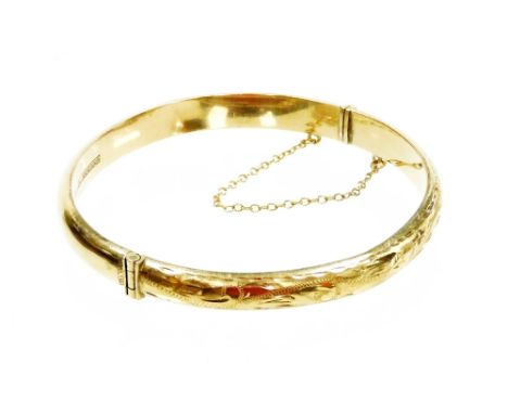 A 9ct gold bangle, with foliate engraved decoration, on a snap clasp, with safety chain as fitted, 8.7g. 