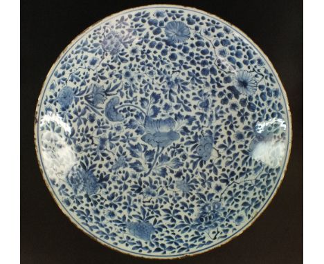 A large Chinese blue and white charger, Qing Dynasty, Kangxi period, painted densely with a foliate design around a central b