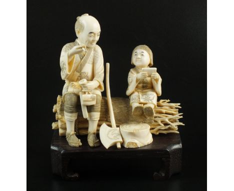 A Japanese ivory okimono of a woodsman sitting on a bundle of twigs with a young child, late Meiji period, the man holding a 