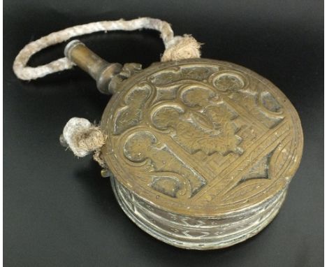 A Moroccan brass powder flask, late 19th/ early 20th century, of circular form with flat sides, with spout and twin set loops