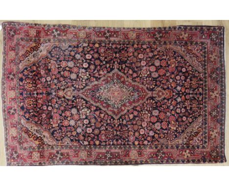 A NORTH WEST PERSIAN RUG with central diamond motif within a floral surround, worked in reds and pale pinks against a dark gr