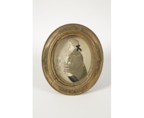 A GEORGE III STYLE RELIEF PORTRAIT OF A GENTLEMAN in period costume holding a glass, with raised fabric coat, in gilt frame, 