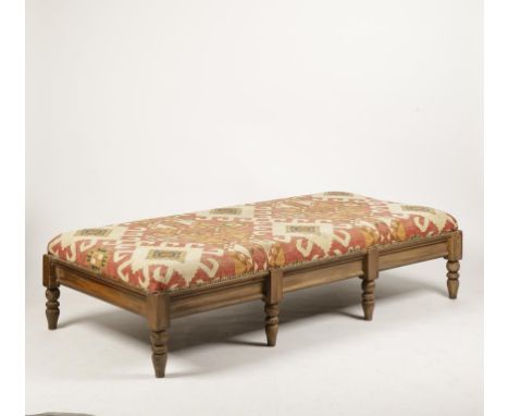 A VICTORIAN STYLE DAY BED or pouffe, the upholstered seat covered in kelim-type fabric on a moulded base and eight turned leg