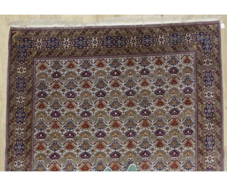 A NORTH WEST PERSIAN CARPET, the central ground worked with repeated geometric motifs against a cream ground within a multigu