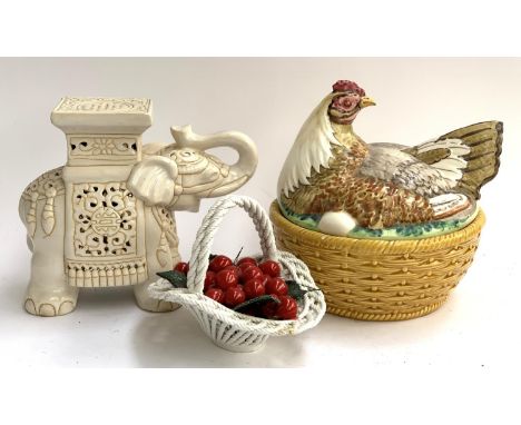 A ceramic elephant pot stand, together with a lidded chicken crock and a basket of cherries 