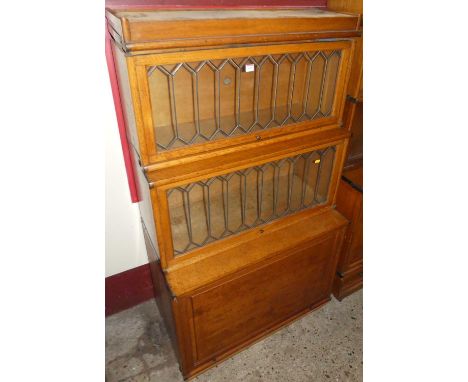 A circa 1930s blond oak Globe Wernicke three-tier stacking bookcase, having two lead glazed sections, with panelled lower dee