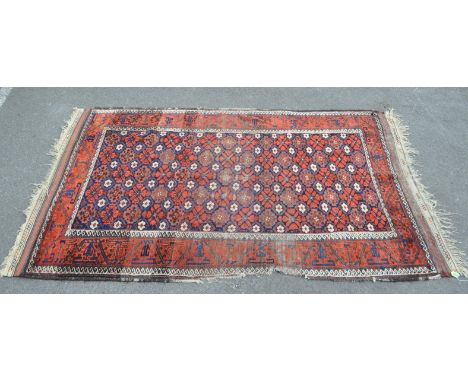 A 20th century Persian Baluch carpet floor rug. The rug featuring a red ground, with repeating floral motfis to central field