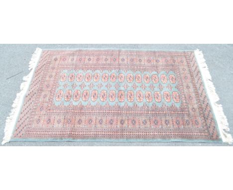 A vintage 20th century Persian Bokhara carpet floor rug. The rug having teal central field populated with a series of repeati