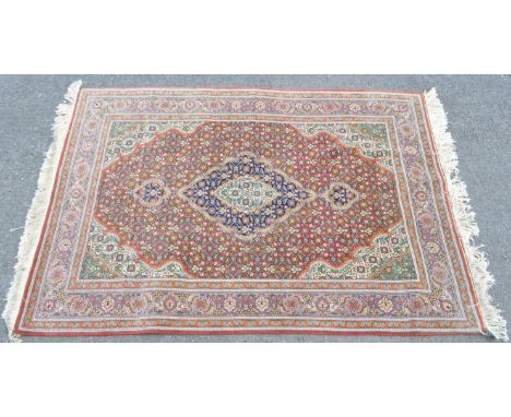A vintage 20th century small Persian Hamadan style rug. The rug of small porportions. The rug having red ground with large ce